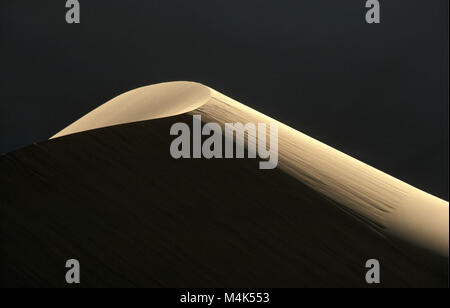 Algeria. Kerzaz. Western Sand Sea. Grand Erg Occidental. Sahara Desert. Last sunrays shining on Sand Dune. Stock Photo