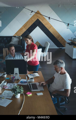Business colleagues discussing over computer at desk Stock Photo