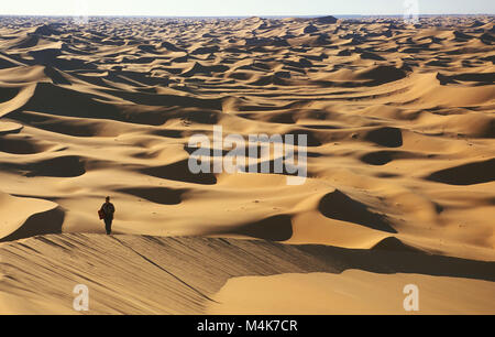 Algeria. Taghit or Tarit. Western Sand Sea. Grand Erg Occidental. Sahara desert. Sand dunes. Sand sea. Tourist, woman walking, hiking. Stock Photo
