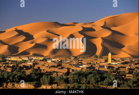 Algeria. Kerzaz. Western Sand Sea. Grand Erg Occidental. Sahara desert. Panoramic view of oasis, village, Mosque and dunes, sand sea and palm trees. Stock Photo