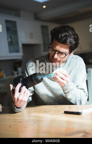 Man cleaning lens of digital camera at home Stock Photo