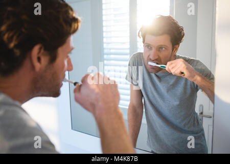 Man looking at mirror and brushing his teeth in bathroom Stock Photo