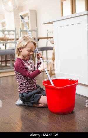 Boy holding floor mop with bucket Stock Photo