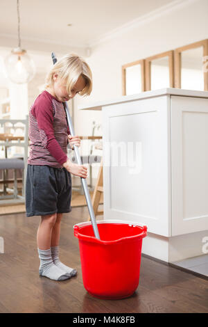 Boy holding floor mop with bucket Stock Photo