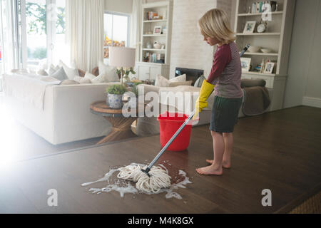 Boy washing the floor with mop in living room Stock Photo