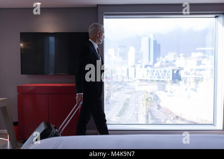 Businessman with luggage looking outside the window Stock Photo