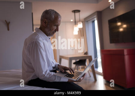 Businessman using a laptop on bed Stock Photo