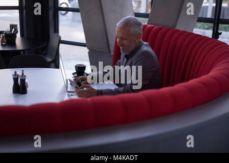 Businessman using mobile phone while working on laptop Stock Photo