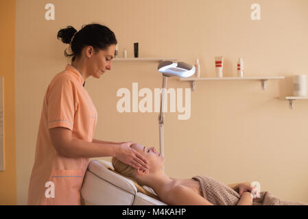 Beautician giving face massage to female customer Stock Photo