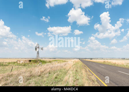 A farm scene with water-pumping windmill and dam next to the R703-road between Verkeerdevlei and Excelsior in the Free State Province of South Africa Stock Photo