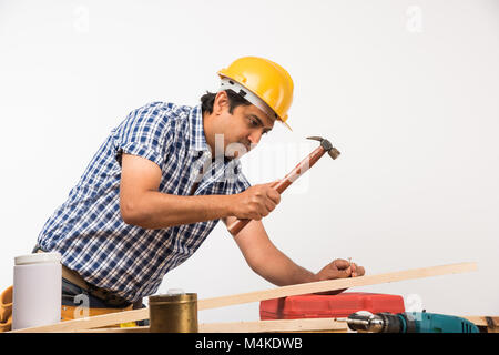 Handsome Indian Carpenter or wood worker in action, isolated over white background Stock Photo
