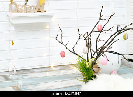 Studio shot of Easter decorations with colorful eggs hanging on twigs in light room Stock Photo
