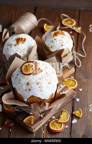 Easter cakes with candied fruits and almond crumbs wrapped in kraft paper on brown wooden table Stock Photo