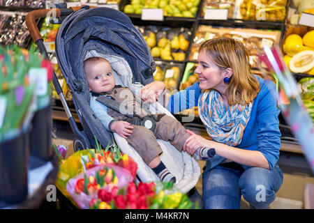 Young woman with baby son in grocery store Stock Photo