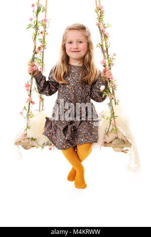 pretty little girl playing on decretive swing, happy and having fun, 4 year old girl Stock Photo