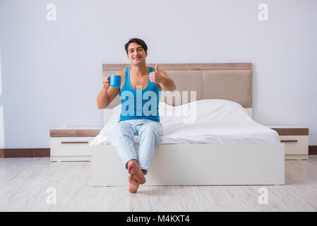 Young man waking up in bed Stock Photo
