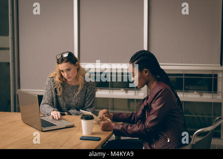 Female executives using laptop and digital tablet Stock Photo