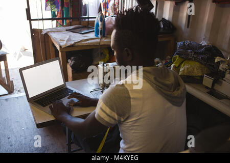 Tailor using laptop in shop Stock Photo