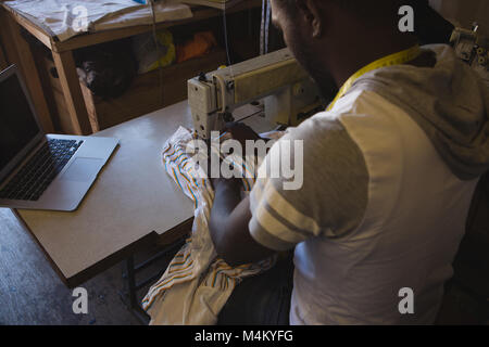 Tailor sewing clothes on sewing machine Stock Photo