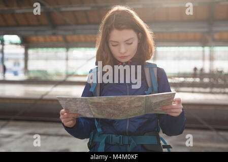 Traveler with backpack looking at map while waiting for train Stock Photo