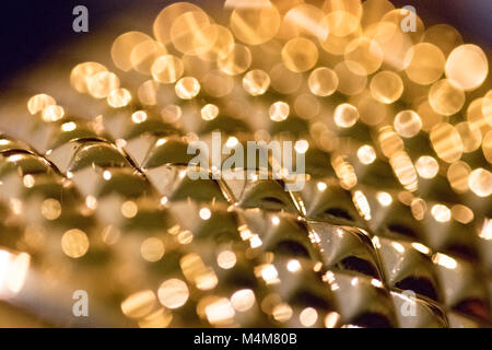 Golden sparkles reflecting from shiny patterned surface. Close up/macro. Stock Photo