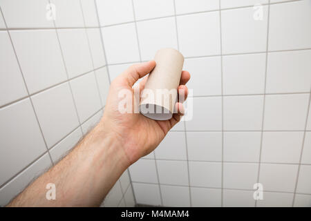 Close-up Of A Man's Hand Holding Empty Toilet Paper Roll In Bathroom Stock Photo