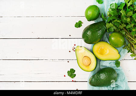 Ripe avocado, lime and cilantro on a light wooden table. Healthy food concept. Top view Stock Photo