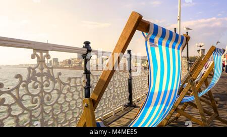 Empty deck chairs billowing invitingly in the summer breeze, on Brighton's famous Palace pier, also called Brighton Pier its world famous Stock Photo
