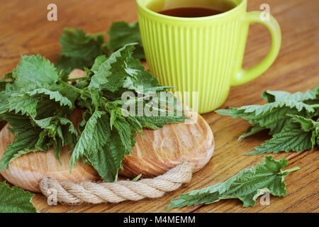 stinging nettle on a cutting board and tea cup Stock Photo