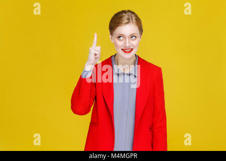 Ginger red head business woman in red suit have good plan, idea. Studio shot, isolated on yellow background Stock Photo