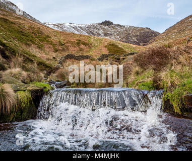 Winter view of Crowden Brook on Kinder Scout in the Derbyshire Peak District with Crowden Tower on the horizon Stock Photo