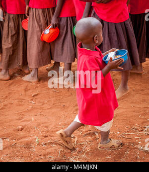 Children queueing for a lunchtime stew made with beans maize and onions at Kileva Primary School near Voi in Southern Kenya Stock Photo