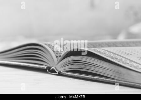 black and white photo of an open book on the table, selective focus and shallow depth of field Stock Photo