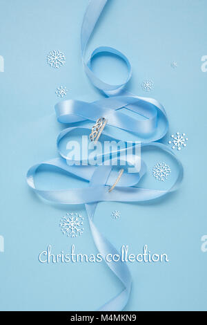 Creative concept photo of christmas tree made of ribbon and  jewellery on blue background. Stock Photo