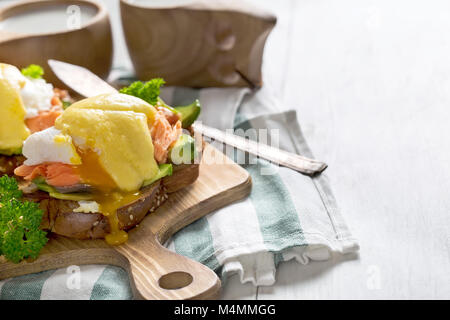 Eggs benedict, scandinavian style - with avocado and poached salmon. Copy space background. High key. Stock Photo