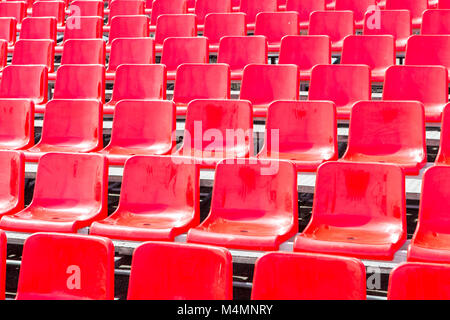 Rows empty bright red plastic seats in a stadium Stock Photo