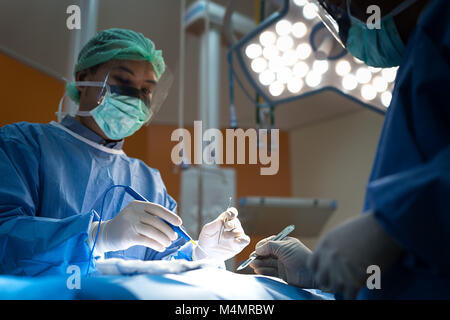 Asian doctor and an assistant in the operating room for surgical venous vascular surgery clinic in hospital. Stock Photo