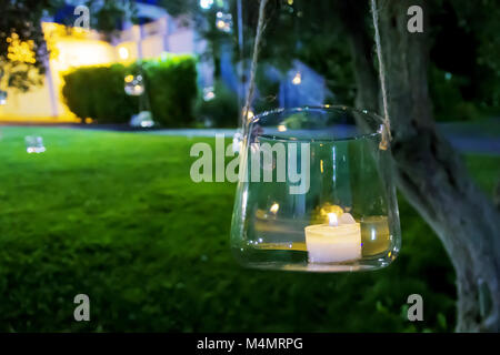 candle in a glass hanging from a tree Stock Photo