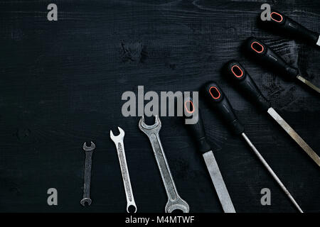 Series of many sharp steel blades and wrenches on black wooden background. Set of chisels. Top view. Copy space. Still life. Flat lay Stock Photo