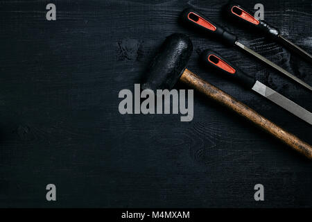 Series of many sharp steel blades and hammer on black wooden background. Set of chisels. Top view. Copy space. Still life. Flat lay Stock Photo