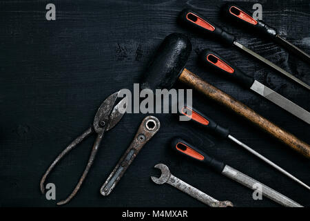 Series of many sharp steel blades and hammer on black wooden background. Set of chisels. Top view. Copy space. Still life. Flat lay Stock Photo