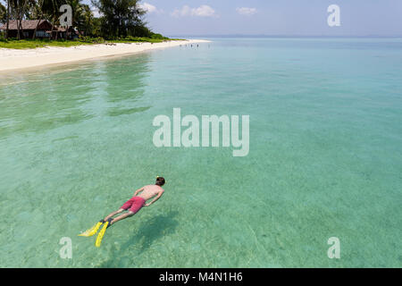 Snorkeller in red swimsuit swimming in crystal clear turquoise tropical sea water on paradise island Stock Photo