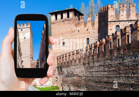 travel concept - tourist photographs walls of Castelvecchio (Scaliger) Castel in Verona city in Italy on smartphone Stock Photo