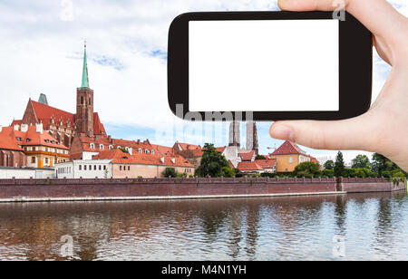 travel concept - tourist photographs Churches and Cathedral on Ostrow Tumski in Wroclaw city in Poland from Oder River in autumn on smartphone with cu Stock Photo