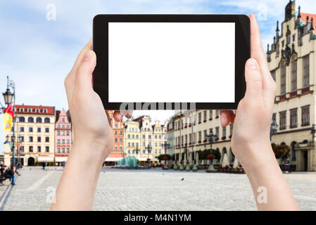 travel concept - tourist photographs central Market Square (Rynek) in Wroclaw city in Poland in autumn morning on tablet with cut out screen for adver Stock Photo