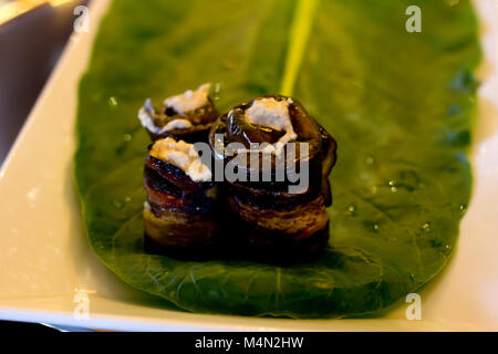 Rolls of eggplant with a filling of walnuts, laid out on the sheet of chard Stock Photo