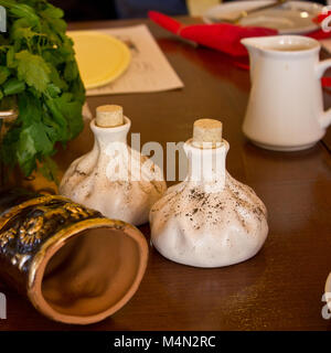 Horn for wine, salt and pepper shakers in a form of khinkali and spinach in a bowl on the table Stock Photo