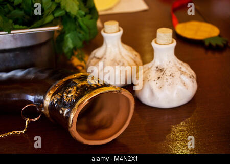 Horn for wine, salt and pepper shakers in a form of khinkali and spinach in a bowl on the table Stock Photo