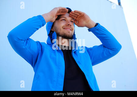 Positive man in blue hoodie looking up. Stock Photo
