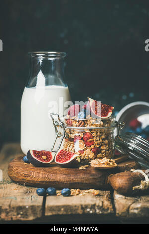 Healthy vegan breakfast. Oatmeal granola with bottled almond milk, honey, fruit and berries over rustic wooden table background, copy space. Clean eat Stock Photo